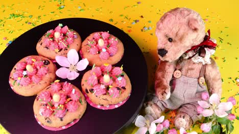 galleta decorada con crema de vainilla girar lentamente en la mesa giratoria negra en la luz rosa. oso de peluche. dulces y postres hechos en la cocina doméstica.