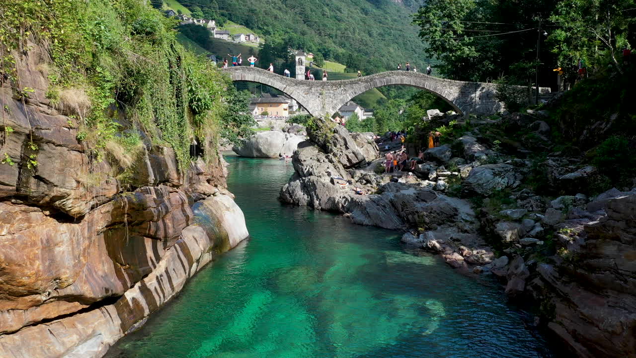 toma de drones de ponte dei salti el puente peatonal de piedra medieval de doble arco sobre el agua clara del río verzasca
