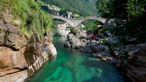 drone shot of ponte dei salti the double-arched medieval stone pedestrian bridge over the clear water of the verzasca river