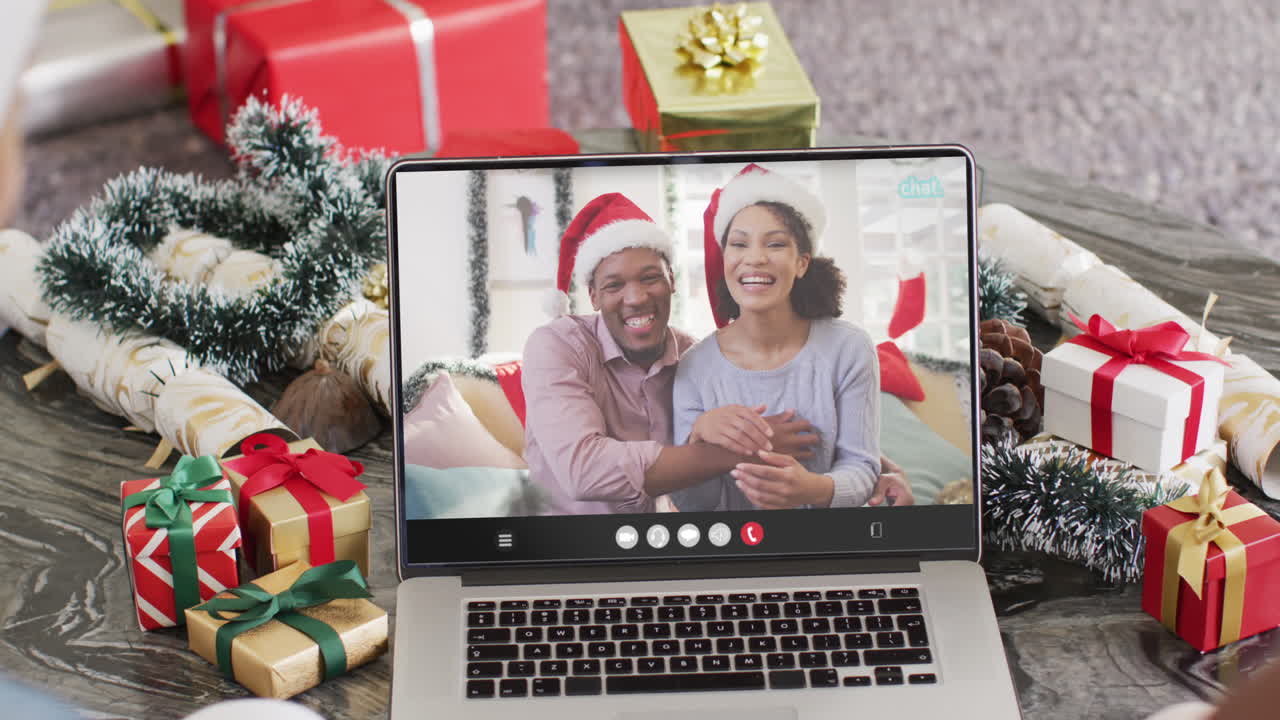 amigos diversos con sombreros de santa teniendo llamada de video portátil con pareja feliz diversa