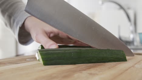 cortando pepinos en el tablero con un cuchillo enorme en la cocina