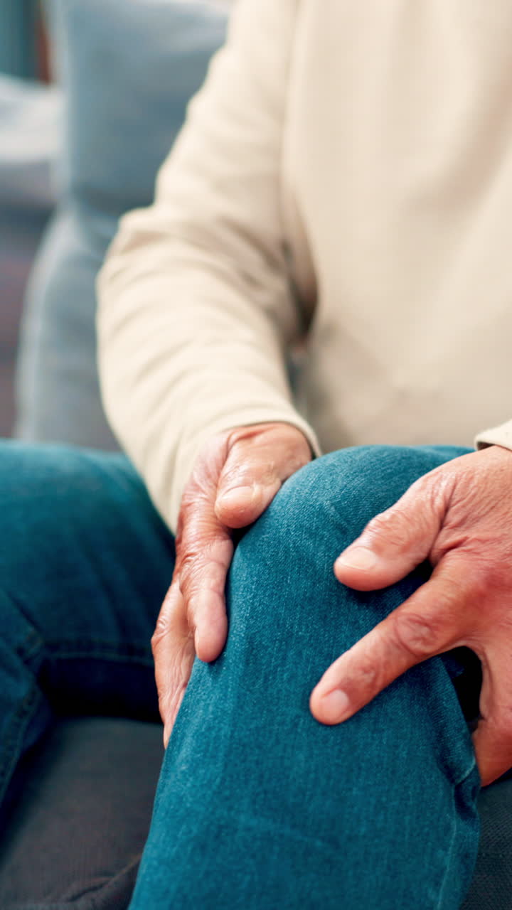Close Up of Senior Person's Hands Holding Knee in Pain