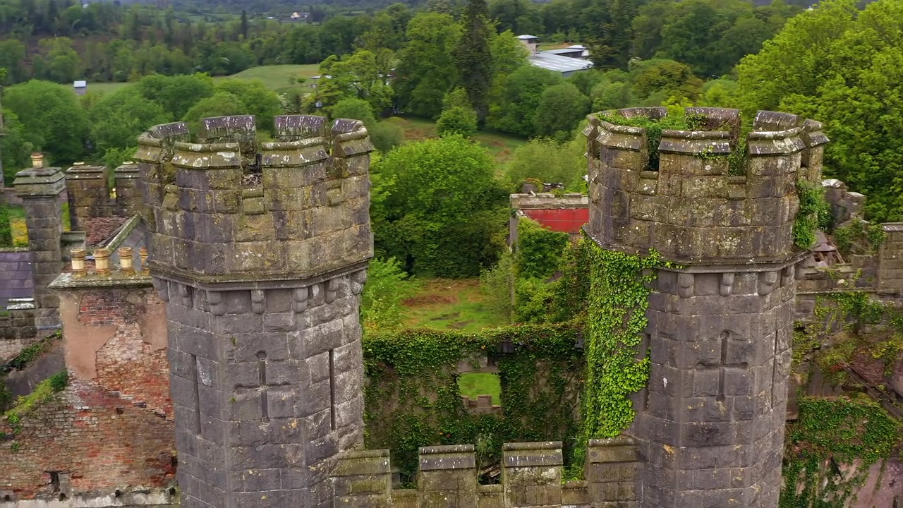 Orbita aerea fluida al rallentatore delle torri gemelle laterali del Castello di Saunderson, che mostrano feritoie a forma di croce e la muratura di fortificazione gotica. Irlanda