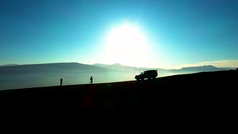 Silhouette-Of-A-Running-Man-Towards-Parked-Vehicle-Backlit-Bright-Sunlight-During-Sunset