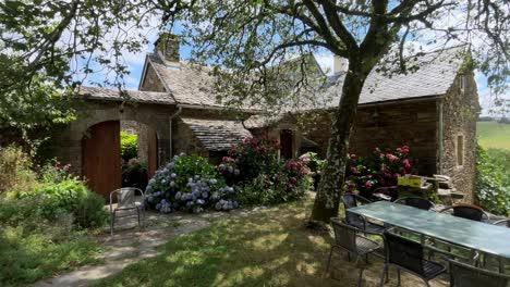 In-the-courtyard-of-the-stone-house-filled-with-hydrangea-flowers,-outdoor-tables-and-chairs-are-placed
