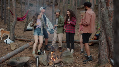 friends dancing around a campfire in the forest