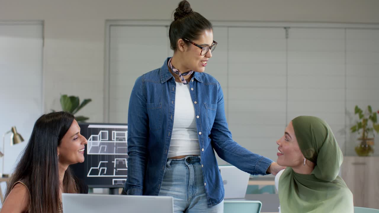 Diverse colleghe che collaborano alla scrivania esaminando i progetti e accolgono la collega che porta il caffè