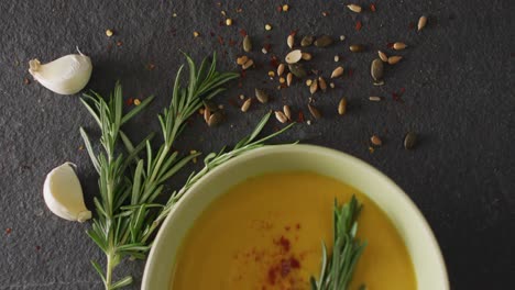 video of cream vegetable soup in bowl on grey table with rosemary