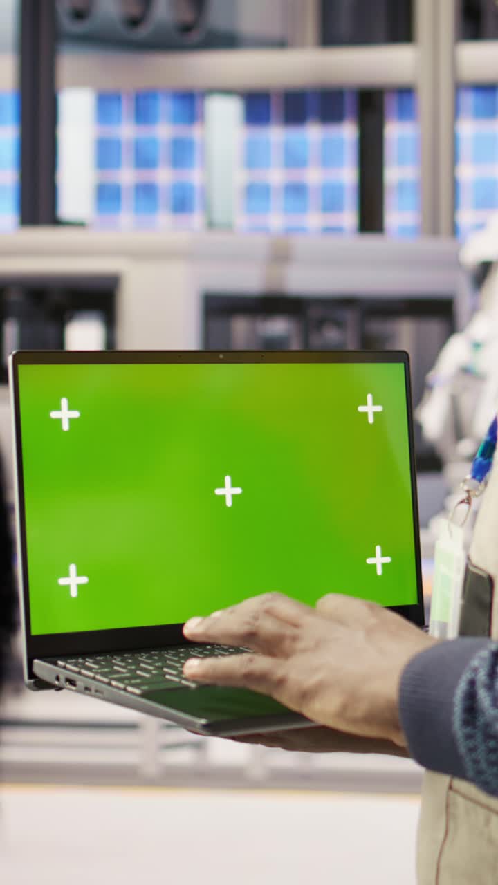 Vertical video Factory engineer using green screen laptop to calibrate high tech machinery
