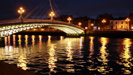 illuminated bridge over a river at night with city lights reflected on water