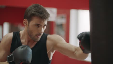 kickboxer man training punches on combat bag in fight club.