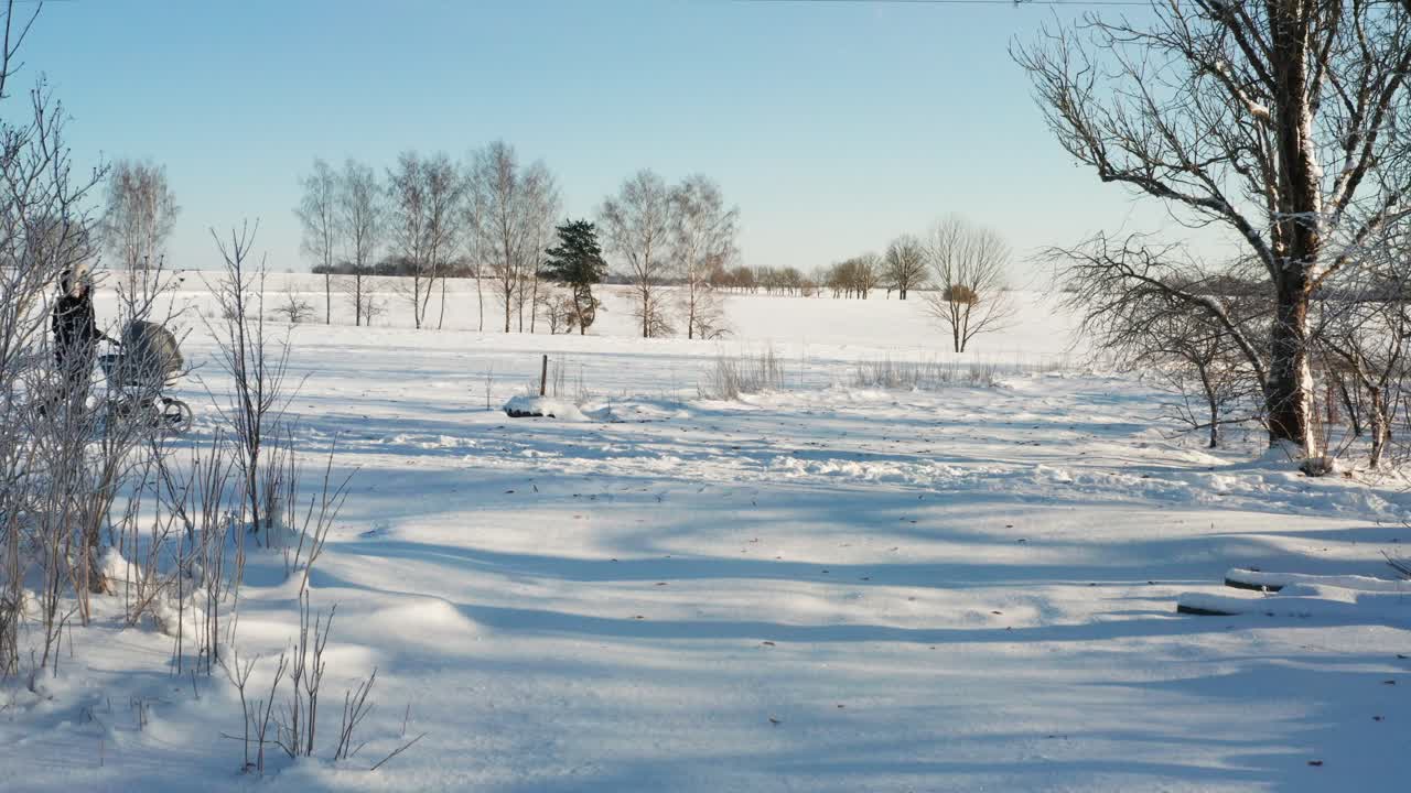 독신 어머니는 눈이 많이 내리고 밝은 겨울날에 아기 마차와 함께 산책하는 것을 즐긴다.