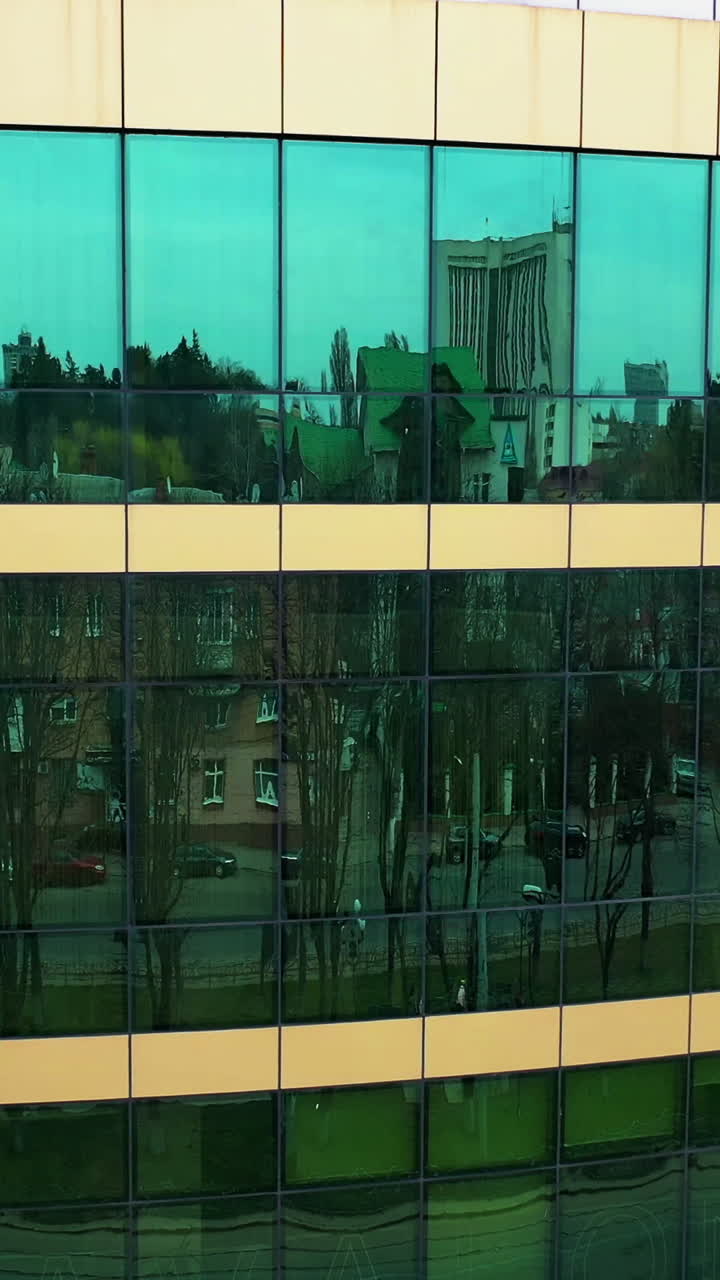 Facade of modern glass building. Surface of glass building with the city reflection. Vertical video