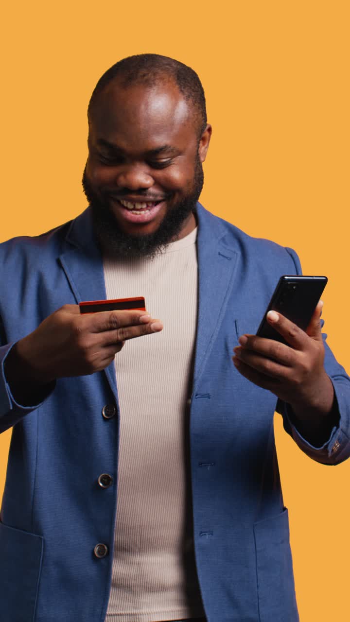 Vertical video Happy man adding payment method on phone website, studio background