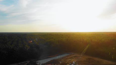 Cinematic-4K-Drone-Footage-of-Onshore-Drilling-Rig-equipment-structure-for-oil-exploration-and-exploitation-in-the-middle-of-jungle-surrounded-by-palm-oil-trees-during-sunset-and-high-oil-price