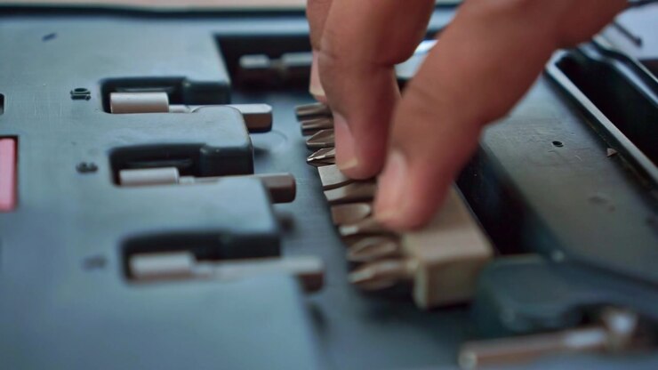 fingers inserting a screwdriver bit into its case slot. Tool footage highlighting precision, organization, and workshop maintenance.