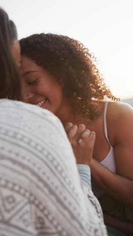 vertical video of happy biracial female couple embracing in garden in slow motion