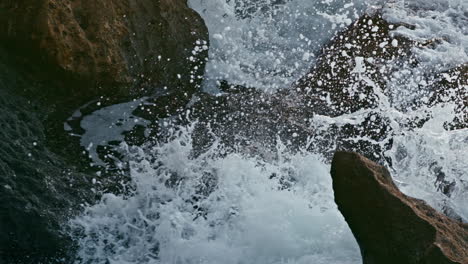 Ocean-splashes-foaming-hill-outside-closeup.-White-spray-breaking-by-huge-rocks