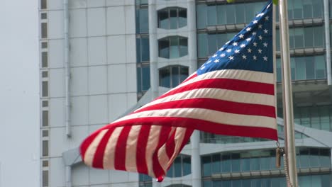 an united states flag waving in the wind in front of the us consulate in hong kong