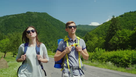 una joven pareja de turistas camina por el camino hacia hermosas montañas cubiertas de bosques forma activa de