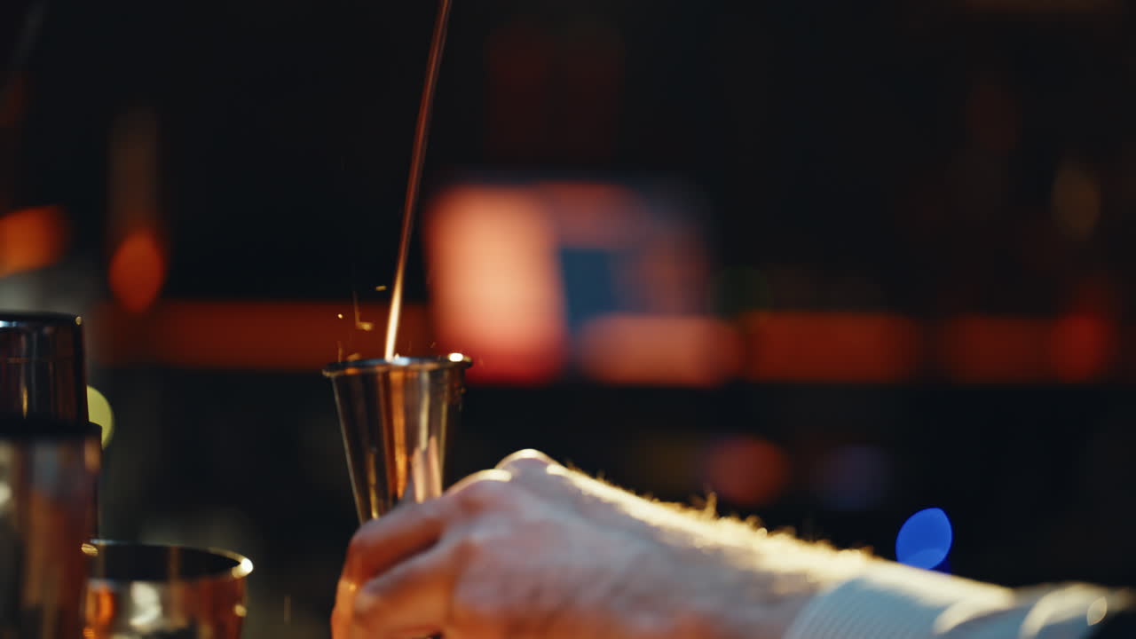 Nærbillede af bartender, der hælder spiritus i målebæger i natklub.