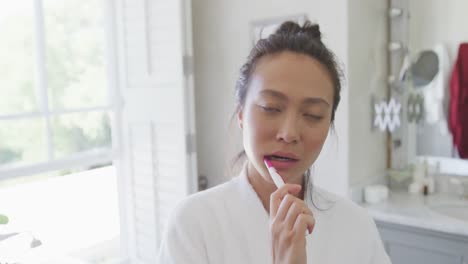 Happy-asian-woman-brushing-teeth-in-bathroom,-in-slow-motion