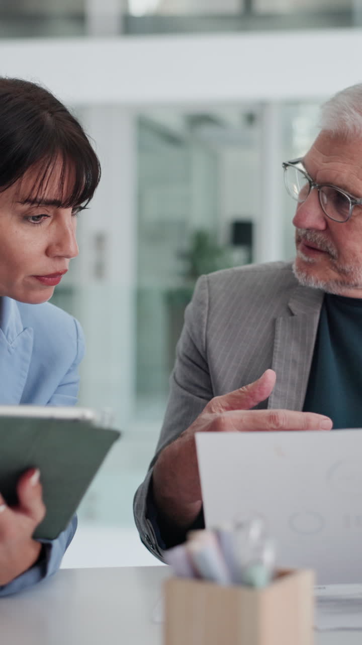 Colleghi di lavoro che discutono documenti e un tablet in una riunione d'ufficio