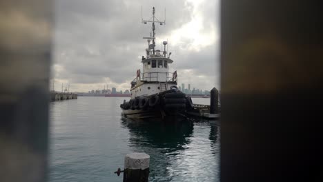 push in of tug boat docked at pier through waterfront railing