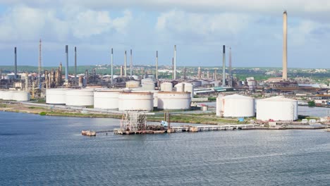 telephoto aerial pan to establish rows of flare stacks and storage tanks in coastal environment