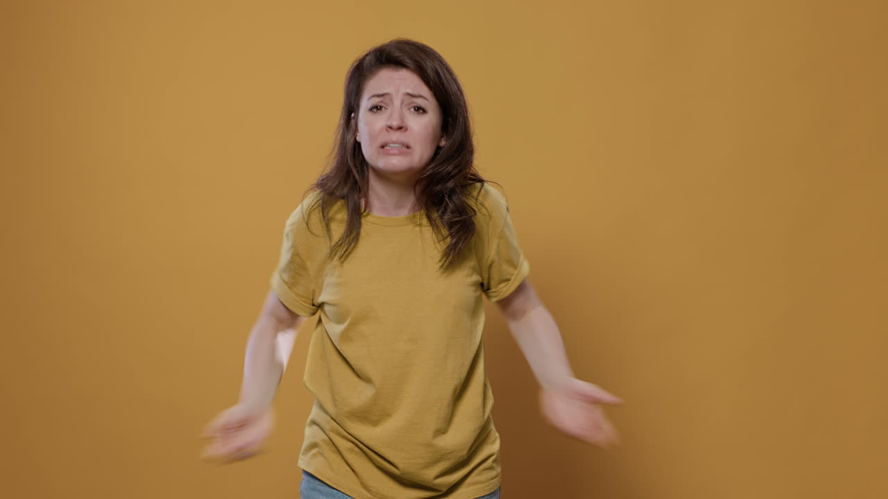 Woman gesturing in front of a yellow background