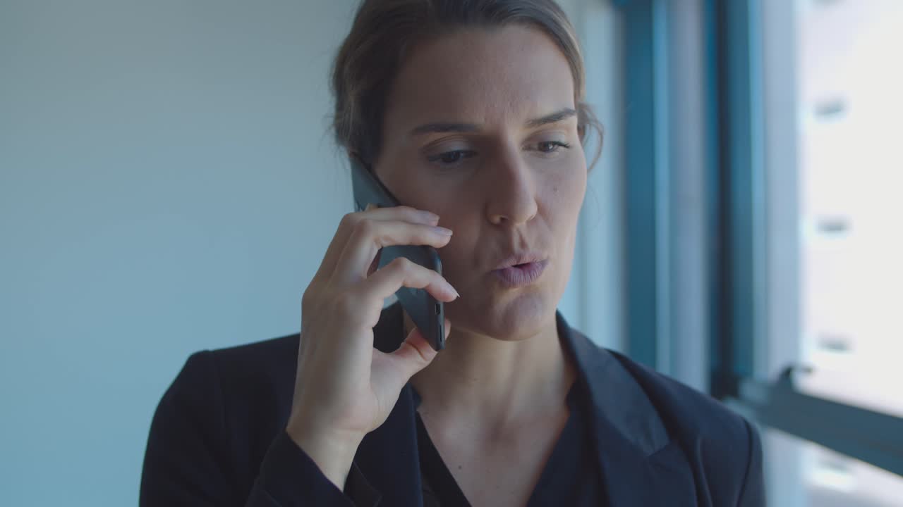 Focused serious businesswoman standing near window