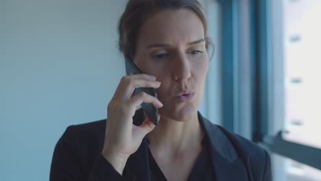 focused serious businesswoman standing near window