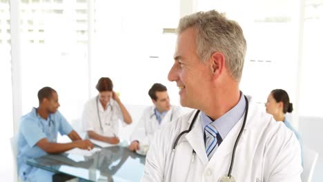 el médico mirando a la cámara y su personal detrás de él