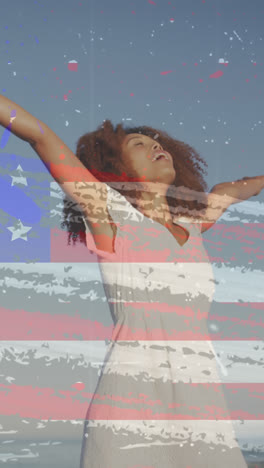 Animation-of-american-flag-over-african-american-woman-raising-hands-at-beach