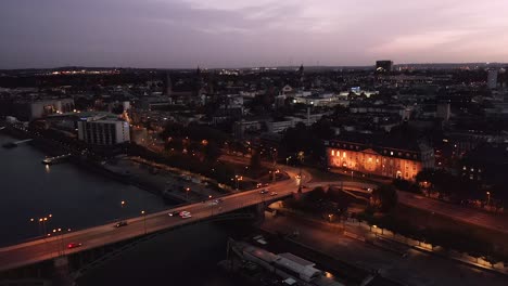 leaving shot of mainz city in germany by night with a drone right after magic hour and sunset showing the old bridge and the city center