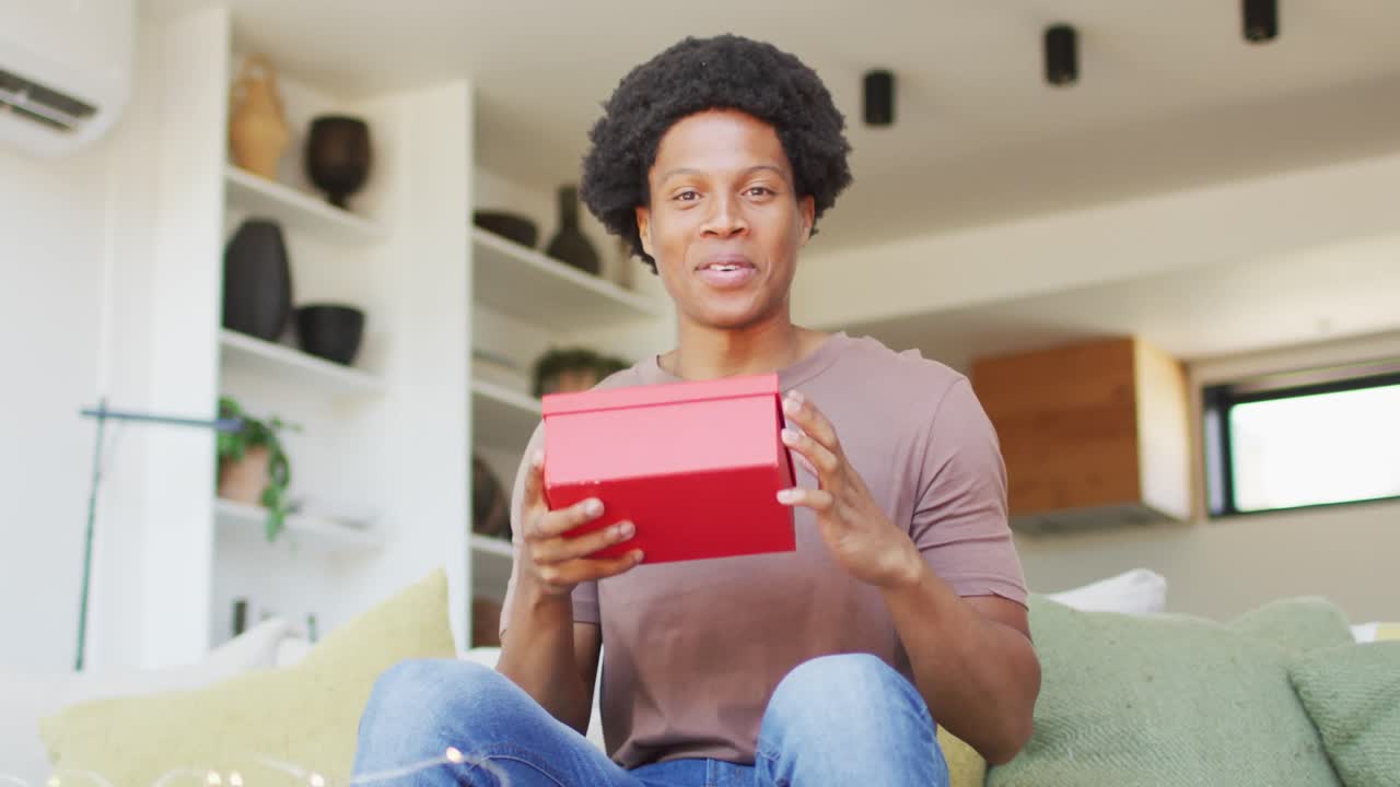 hombre afroamericano abriendo regalo en casa