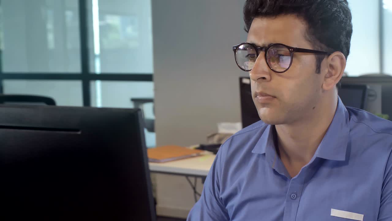 joven empresario con gafas sentado frente a una computadora