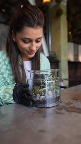 woman caring for a succulent plant in a terrarium