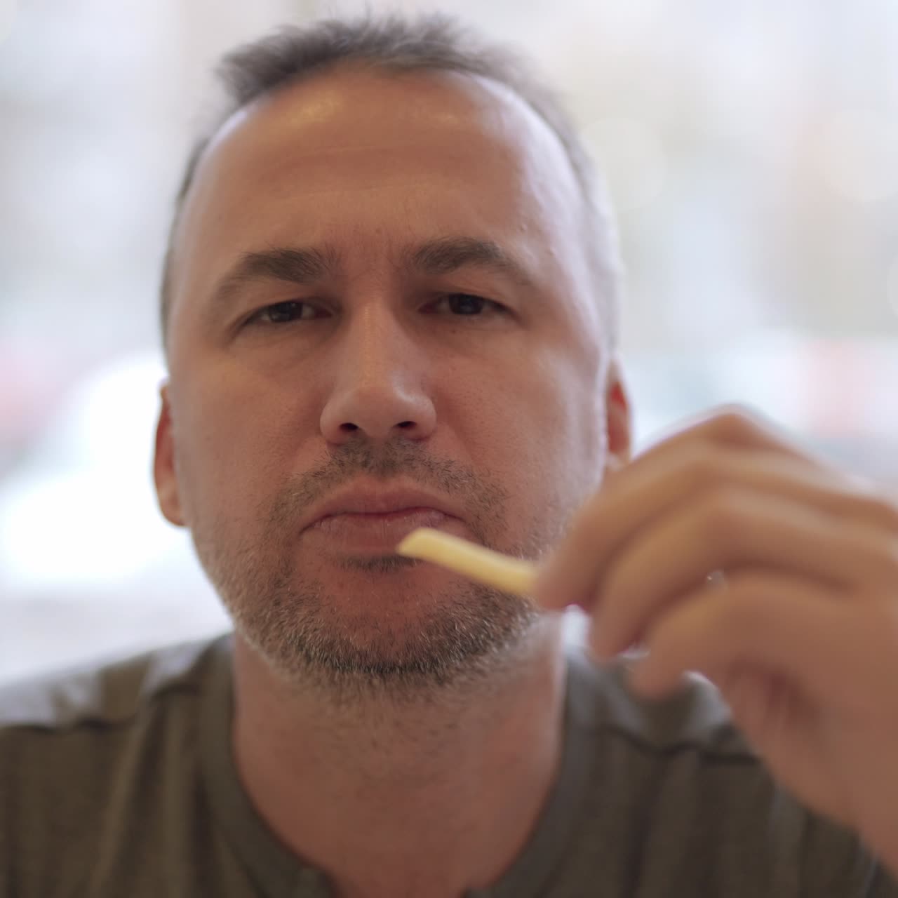 Young man portrait eating french fries in fast food restaurant. Harmful nutrition