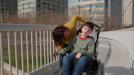 mother and son on wheelchair enjoying a walk on a bridge