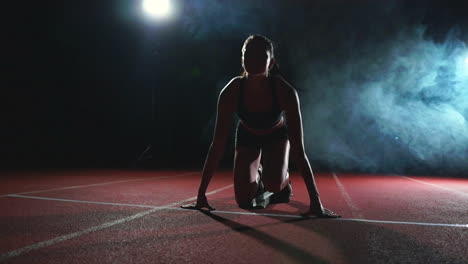 mujer atleta en pantalones cortos negros y una camiseta en zapatillas de deporte están en las almohadillas de carrera en la pista del complejo deportivo y correr en cámara lenta