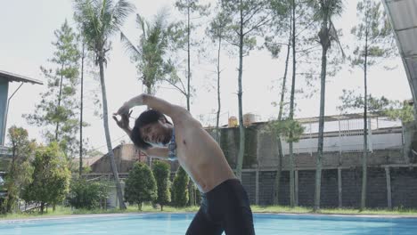 young asian man athlete raising arms stretching his back doing warming up before swimming