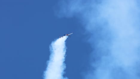 stunt plane executes maneuvers with smoke trails