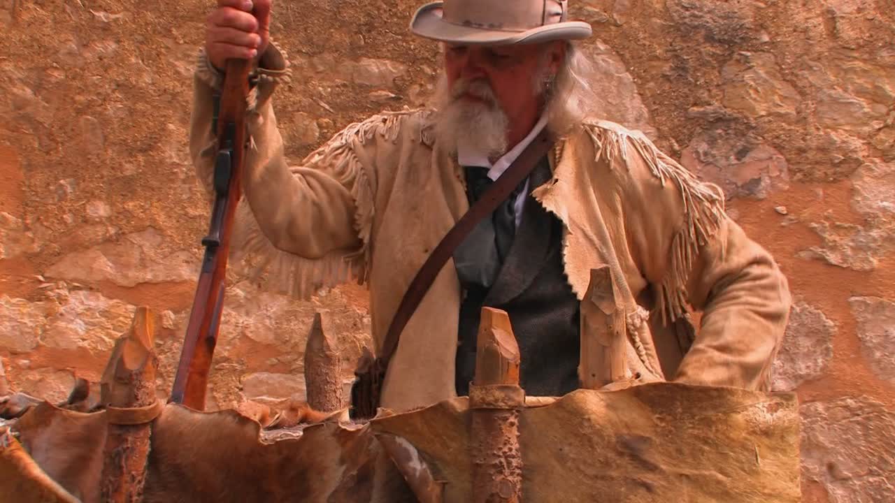 노인은 소총을 들고 가죽 개척자 재킷을 입는다