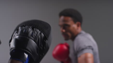 toma de cerca de un boxeador masculino luchando con un entrenador que usa guantes o guantes de puñetazos practicando para la pelea 2