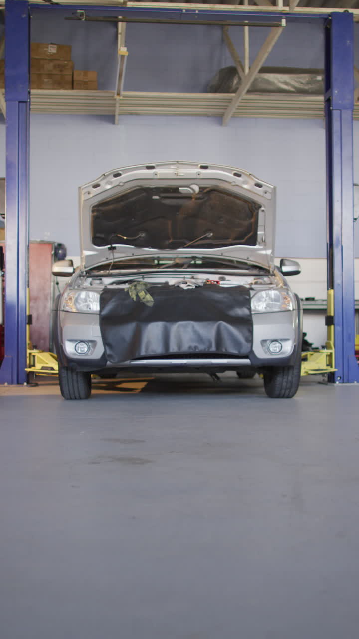 video vertical de un coche con el capó abierto en un taller de reparación de automóviles