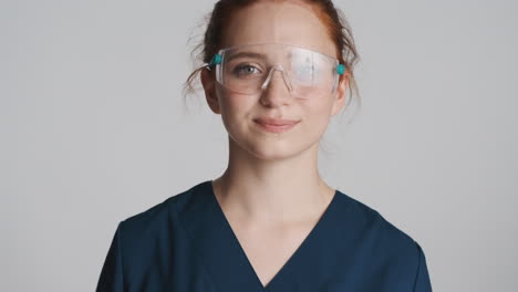 redheaded doctor in front of camera on gray background.