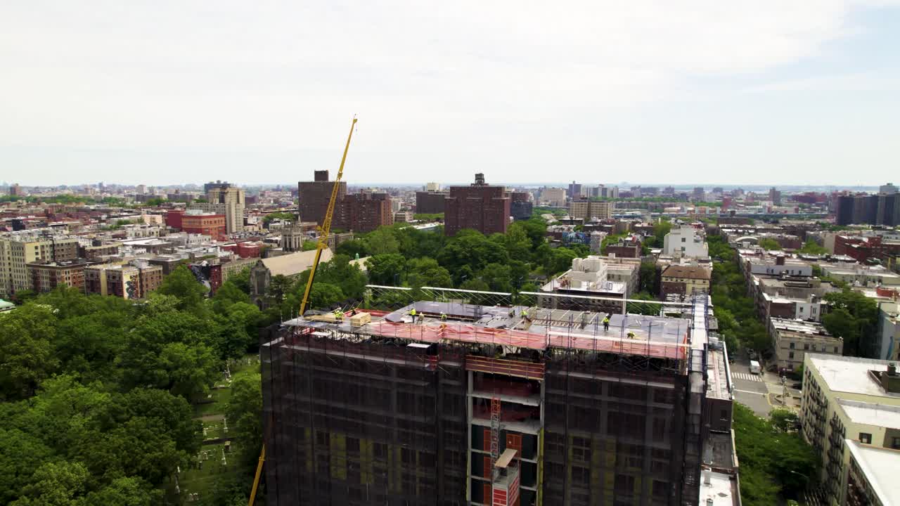 New residential development in Harlem, NYC. 360 drone shot of Manhattan with crane and construction crews at work.