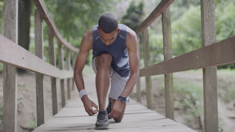 man tying shoe on wooden bridge