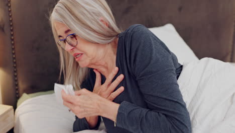 senior woman blowing her nose in bed with tissues